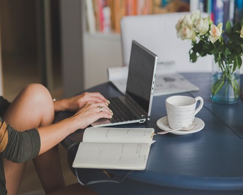 A clean workspace desk with a notepad and coffee